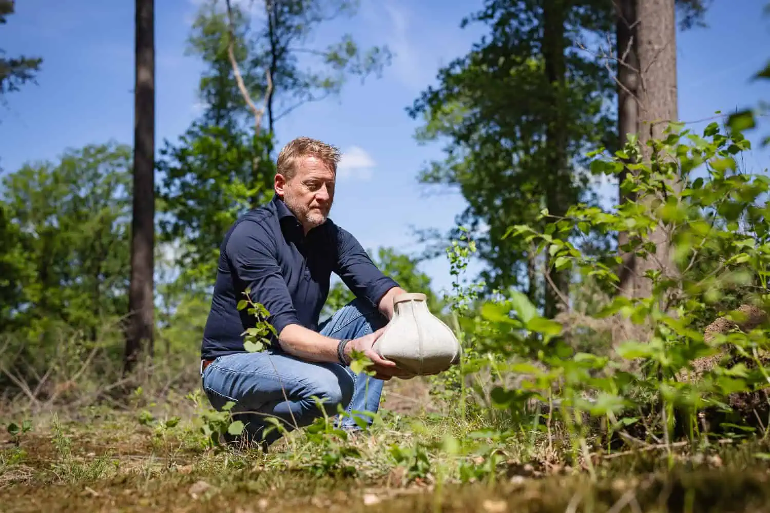Man plaatst Cocoon urn van wolvilt in natuurlijke bosomgeving