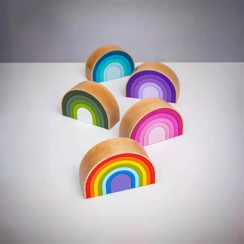 Five wooden semicircular Rainbow urns in all color variants arranged on a white surface: rainbow colors in the foreground, blue and purple at the back, with green and pink in the middle.