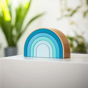 Wooden semicircular Rainbow urn in blue tones, placed on a white surface with plants in the background.