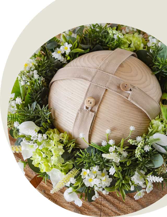 Close-up van de houten Still urn met stoffen riem, geplaatst in een krans van witte bloemen en groen op een houten boomschijf