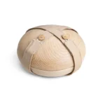 Close-up van de gesloten houten Still urn met beige stoffen riem en houten knopen, gefotografeerd van schuin boven op witte achtergrond
