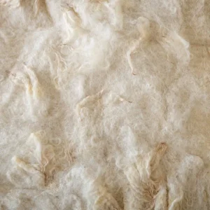 Close-up van de witte gevilte wol waarin zacht licht de structuur en wolkrullen laat zien