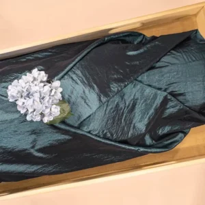 Aqua Blauw lijkwade van glanzende taft, gedrapeerd in een lichte houten kist, met een blauwpaarse hortensia erop.